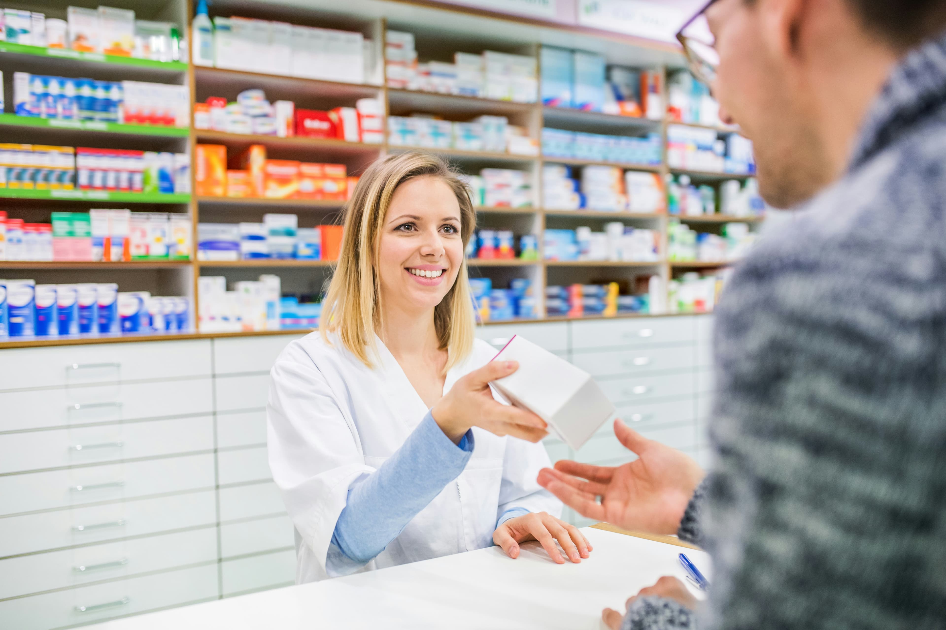 A pharmacist handing a prescription across the counter